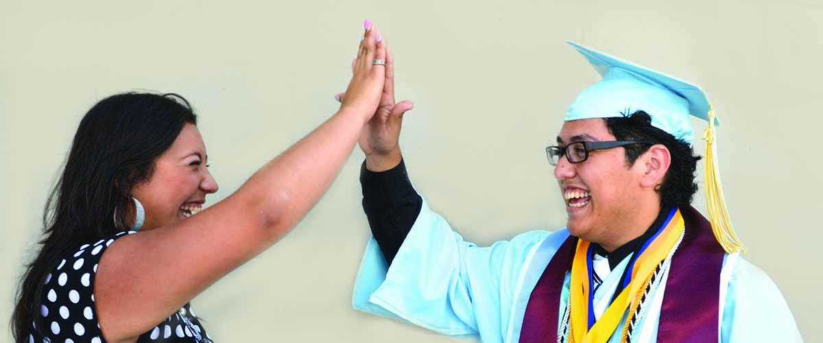 An AVID student celebrating graduation with his teacher